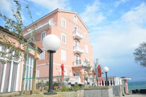 un edificio rosa con el océano en el fondo en Hotel Fiesa, en Piran