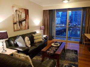 ein Wohnzimmer mit einem Ledersofa und einem Tisch in der Unterkunft Darling Harbour 2 Bedroom Apartment in Sydney