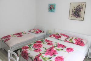 2 Betten in einem Zimmer mit rosa Blumen in der Unterkunft Rooms Jurca in Postojna