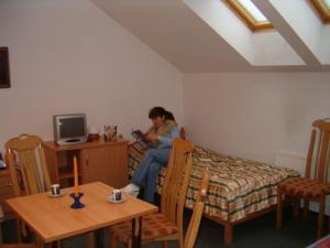 a woman sitting on a bed looking at her cell phone at MOSiR Reda in Reda