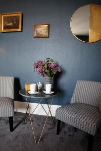 un tavolo con un vaso di fiori e due sedie di La bohème - Chambres d’hôtes a Senlis