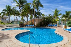 a swimming pool with blue chairs and palm trees at St. James's Club Resort - All Inclusive in English Harbour Town