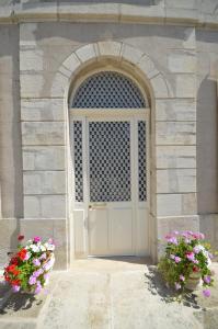 una porta in un edificio in pietra con due fiori di Chambre d'hôtes à TOUL centre ville avec parking privé a Toul