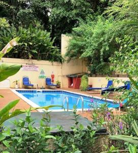 einen Pool im Garten mit Stühlen und Bäumen in der Unterkunft Résidence Bertille Abidjan Cocody in Abidjan