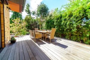 une terrasse en bois avec une table et des chaises. dans l'établissement Willa Laguna, à Kołobrzeg