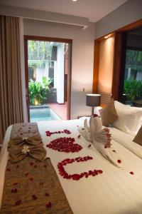 a bed with red rose petals on it at Agranusa Signature Villa Nusa Dua in Nusa Dua