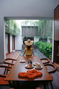 a woman in a hat sitting at a table at Agranusa Signature Villa Nusa Dua in Nusa Dua