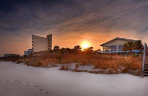 una puesta de sol sobre un edificio y una casa en Oceanfront Litchfield Inn, en Pawleys Island