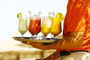 un hombre sosteniendo una bandeja de diferentes bebidas de colores en Oceanfront Litchfield Inn, en Pawleys Island