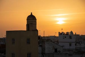 eine Silhouette eines Gebäudes mit Sonnenuntergang im Hintergrund in der Unterkunft Hotel de Francia y París in Cádiz