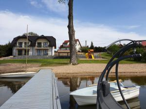 due barche ormeggiate al molo di fronte a una casa di Apartamenty Zełwągi a Mikołajki