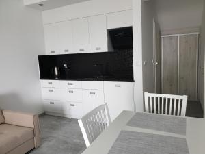 una cucina con armadi bianchi, tavolo e divano di Apartamenty Zełwągi a Mikołajki