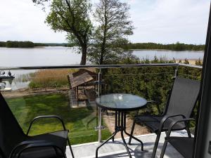 balcone con tavolo, sedie e vista sul lago di Apartamenty Zełwągi a Mikołajki