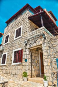 a stone house with red shutters on a building at Villa Marinero in Ulcinj