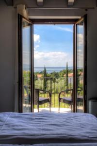 - une chambre avec un lit et un balcon avec vue dans l'établissement Hotel Relais Agli Olivi, à Lazise