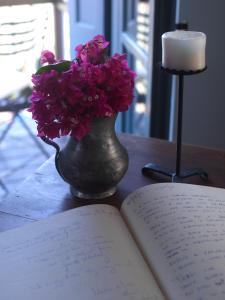 a book and a vase with purple flowers next to a candle at Sto Roloi Island Houses in Poros