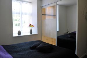 Un dormitorio con una cama y un jarrón con flores en una ventana en AB Centrum Aarhus Bed without Breakfast, en Aarhus