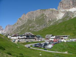 un villaggio con auto parcheggiate accanto a una montagna di Hotel Savoia a Canazei