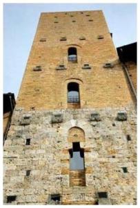 a tall brick tower with windows on a building at La Torre Useppi in San Gimignano