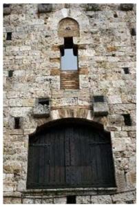 a brick building with a wooden door and a window at La Torre Useppi in San Gimignano