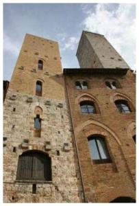 a tall brick building with two towers at La Torre Useppi in San Gimignano