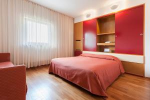 una camera con letto rosso e finestra di Grand Hotel President a Spilimbergo