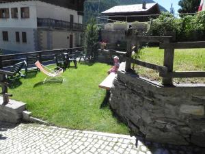 a small child sitting on a bench in a yard at Le Vieux Rascard Chambres d'Hotes in Champoluc