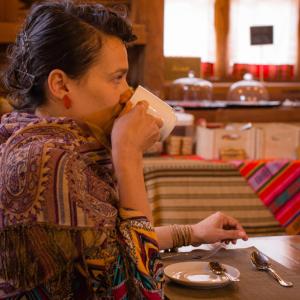 una mujer sentada en una mesa bebiendo de una taza en Terrantai Lodge, en San Pedro de Atacama