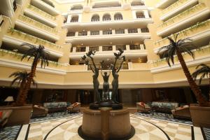 eine Lobby eines Hotels mit Palmen und einer Statue in der Unterkunft Welcomhotel by ITC Hotels, Devee Grand Bay, Visakhapatnam in Visakhapatnam