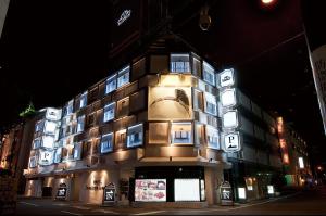 een gebouw met borden aan de zijkant 's nachts bij ホテル ジュエリージュエリー 十三 in Osaka