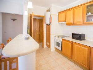 a kitchen with wooden cabinets and a counter top at Apartamentos Quinta da Praia in Alvor