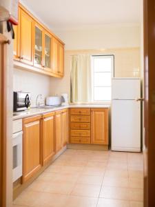 a kitchen with wooden cabinets and a white refrigerator at Apartamentos Quinta da Praia in Alvor