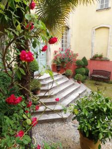 un jardín con flores y plantas rojas y un edificio en Demeure de Digoine "Chambre d'Hotes", en Bourg-Saint-Andéol