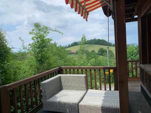 - une terrasse couverte avec une chaise en osier et un parasol dans l'établissement Bed & Breakfast Region Murtensee, à Münchenwiler