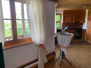 - une cuisine avec un rideau blanc et une table dans l'établissement Bed & Breakfast Region Murtensee, à Münchenwiler