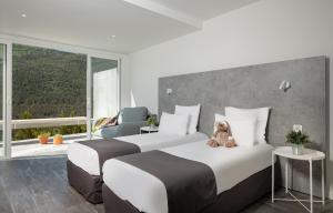 um quarto de hotel com duas camas com um ursinho de peluche em Hotel & Spa des Gorges du Verdon em La Palud sur Verdon