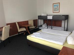 um quarto com um beliche, uma mesa e cadeiras em Hotel-Pension Adamshof em Berlim