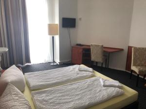 Duas camas num quarto com uma secretária e uma mesa em Hotel-Pension Adamshof em Berlim