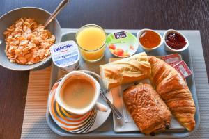 bandeja de desayuno con una taza de café y cruasanes en Hotel l'Europe - Cholet Gare, en Cholet