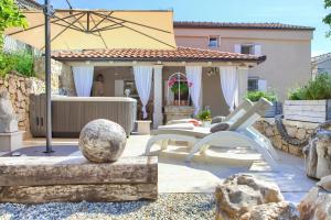 eine Terrasse mit einer Bank und einem Sonnenschirm in der Unterkunft White Cottage Heritage House in Čižići