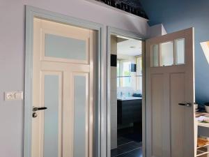 a bathroom with a white door and a sink at Gastenverblijf Neeltje in Oostkapelle