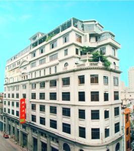 um grande edifício branco com um sinal vermelho em New Asia Hotel em Guangzhou