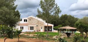 una gran casa blanca con árboles delante de ella en La Casa Menorca, en Ferreries