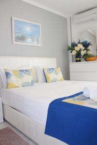 a white bed with blue and yellow pillows in a room at Holidays Nazaré marginal in Nazaré