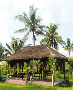 una capanna con tetto di paglia e palme di Namaste Bungalows a Nusa Penida