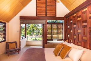 um quarto com uma cama king-size e uma grande janela em Niramaya Villas and Spa em Port Douglas