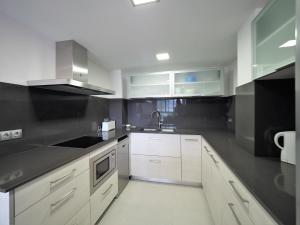 a kitchen with white cabinets and a sink at InmoSantos Oasis A3 in Roses