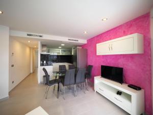 a kitchen and dining room with a pink wall at InmoSantos Oasis A3 in Roses