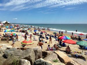 tłum ludzi na plaży z parasolami w obiekcie Pleasant View Inn w mieście Westerly