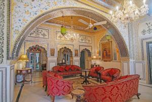 ein verziertes Zimmer mit roten Stühlen und einem großen Bogen in der Unterkunft Alsisar Haveli - Heritage Hotel in Jaipur